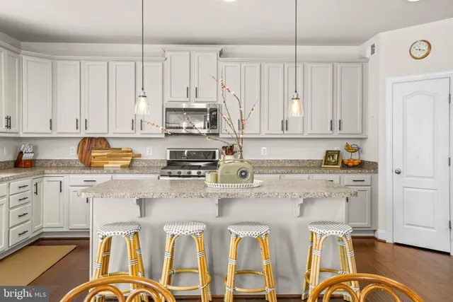 a kitchen with stainless steel appliances granite countertop a stove a sink dishwasher and white cabinets with wooden floor