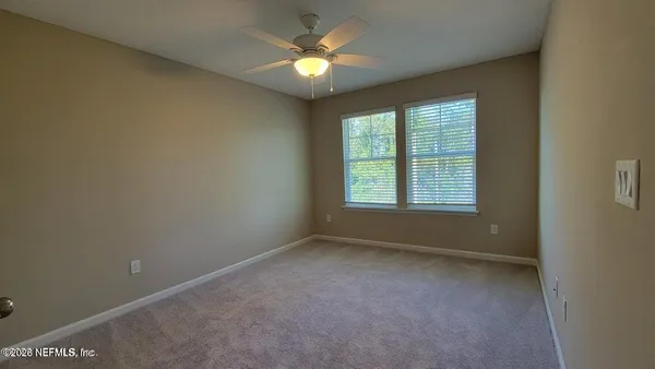 an empty room with a ceiling fan and a window