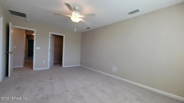 a view of an empty room with a chandelier fan