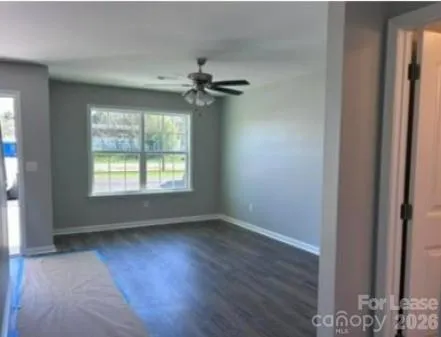 a view of an empty room with a window and wooden floor