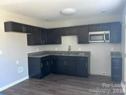 a kitchen with granite countertop a stove a microwave and wooden cabinets