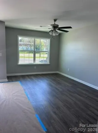 an empty room with wooden floor fan and windows