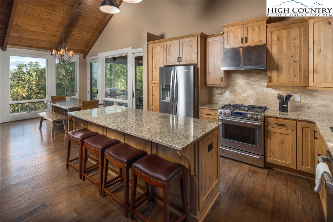 1253 Goldenrod Road Boone, NC 28607 - Photo 6 of 48 a kitchen with stainless steel appliances granite countertop a stove a refrigerator a sink a dining table and chairs with wooden floor