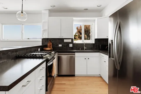 a kitchen with stainless steel appliances granite countertop a lot of counter space and wooden floors