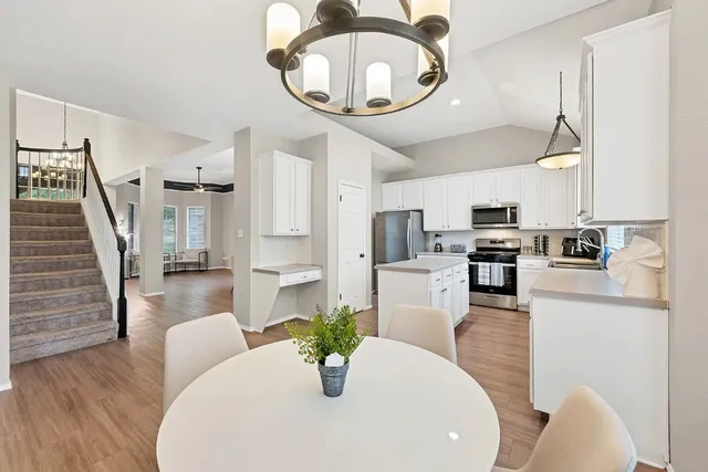 a kitchen with stainless steel appliances kitchen island granite countertop a refrigerator a stove a microwave oven a dining table and chairs with wooden floor