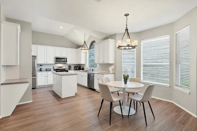 a kitchen with microwave a dining table chairs and refrigerator