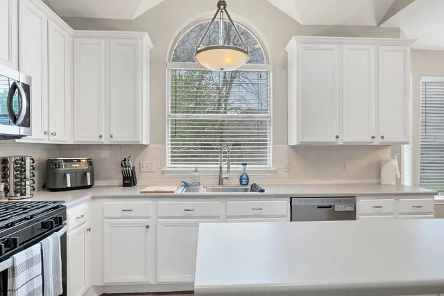 a kitchen with granite countertop a sink white cabinets and a window