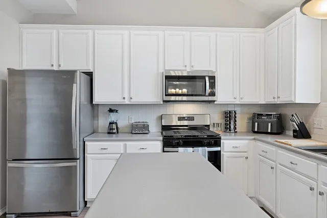 a kitchen with stainless steel appliances white cabinets and a refrigerator