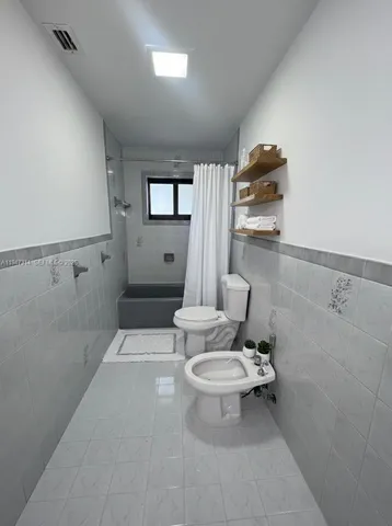 a white toilet sitting next to a bathroom sink and tub