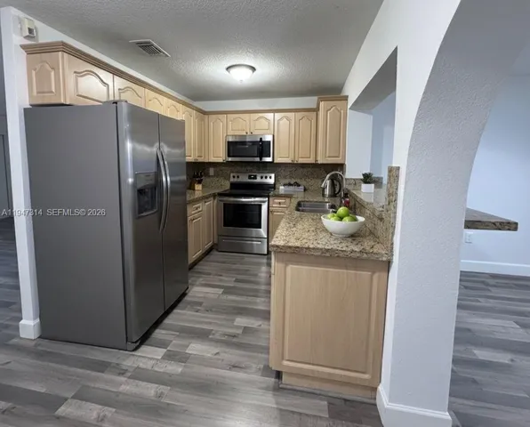 a kitchen with stainless steel appliances granite countertop a refrigerator and a sink