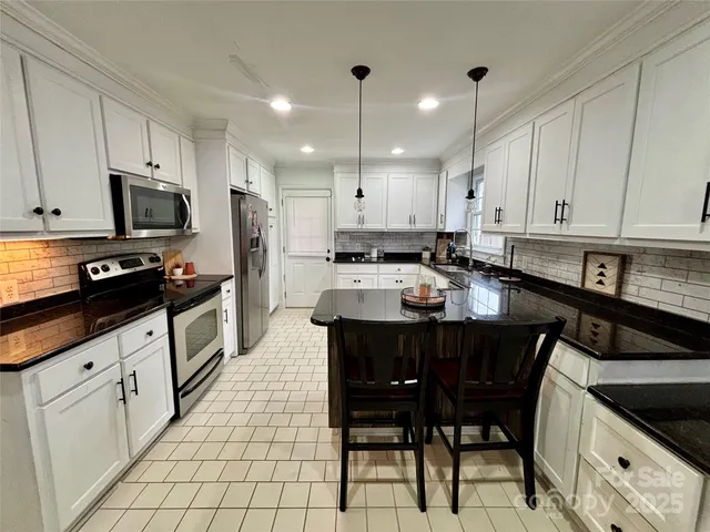 a kitchen with stainless steel appliances granite countertop a stove a sink a microwave and a refrigerator