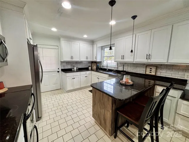 a kitchen with granite countertop a sink a counter top space appliances and cabinets