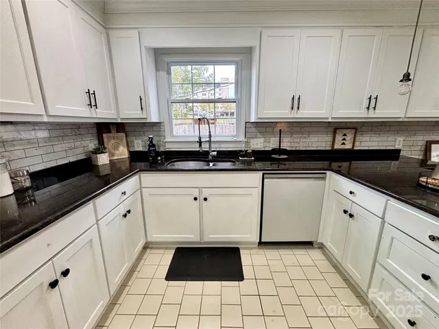 a kitchen with granite countertop white cabinets and sink