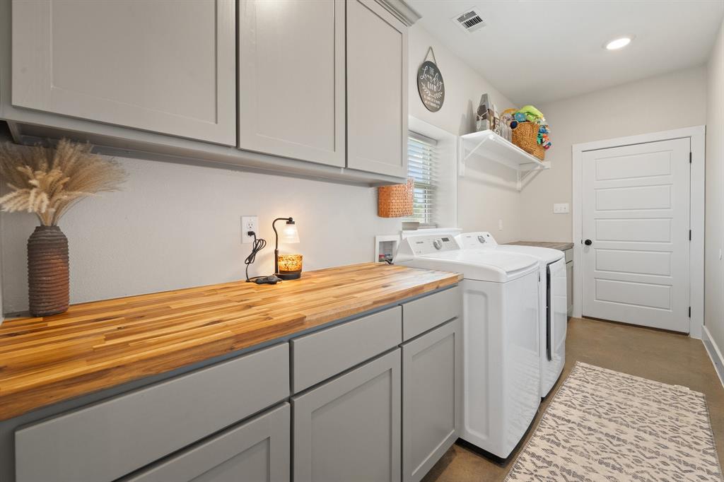 1031 Augustus Court Rio Vista, TX 76093 - Photo 16 of 30 Laundry room featuring a wood-finish countertop, gray cabinetry, upper wall cabinets, a window with blinds, and white paneled door