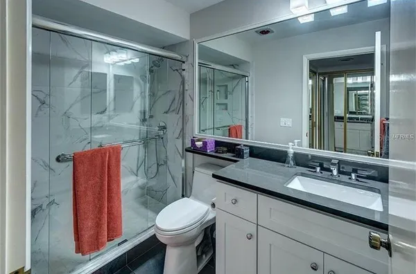 a bathroom with a granite countertop sink toilet and shower