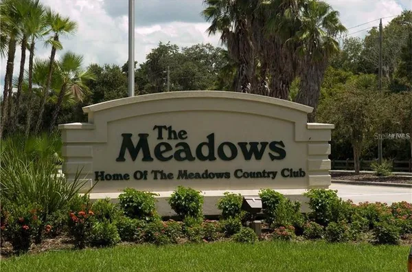 a sign of golf club on a wall under a tree