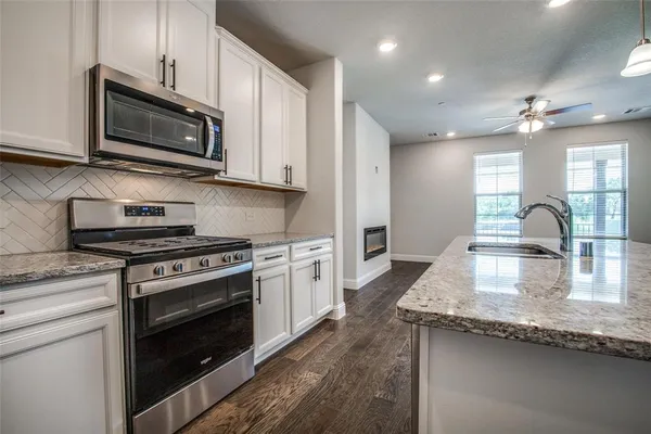 a kitchen with stainless steel appliances granite countertop a sink refrigerator and cabinets