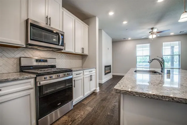 a kitchen with stainless steel appliances granite countertop a sink refrigerator and cabinets