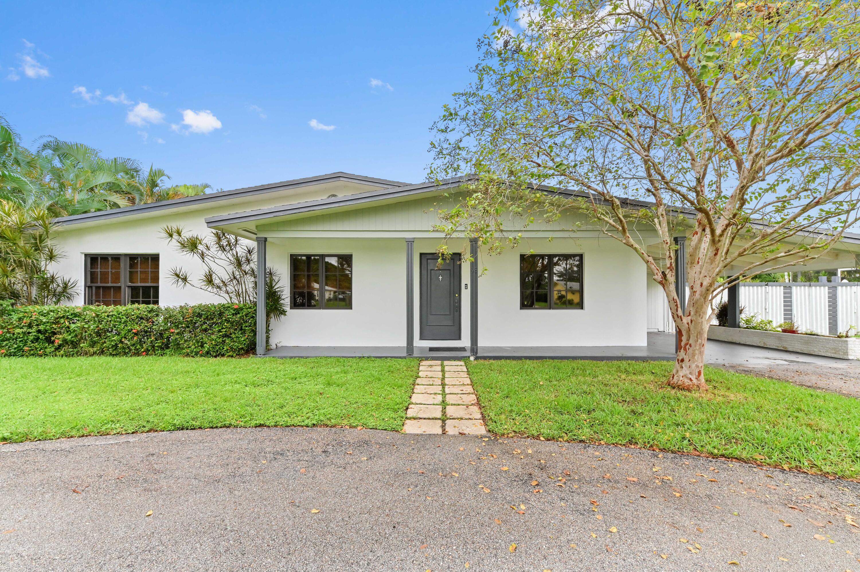 98 Cleveland Road Lake Worth, FL 33467 - Photo 2 of 30 a front view of a house with a garden and trees