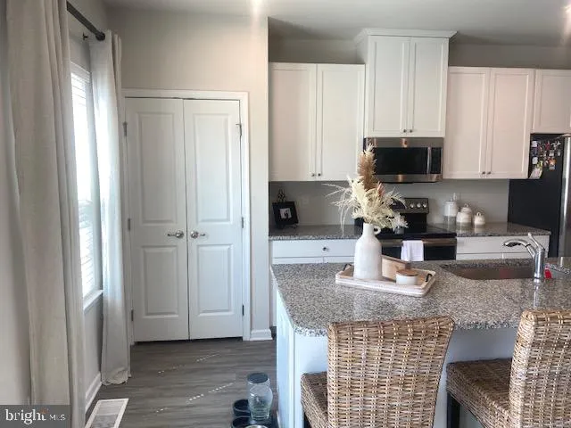 a kitchen with granite countertop a refrigerator stove top oven and sink