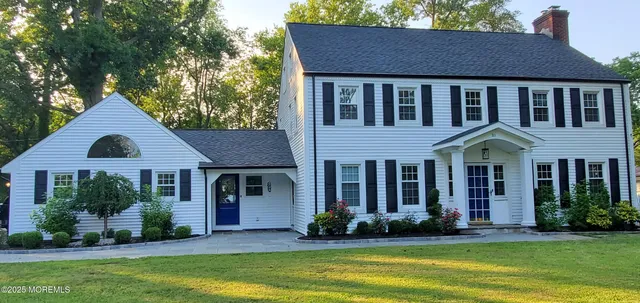 a view of a brick house with a yard plants and a large tree
