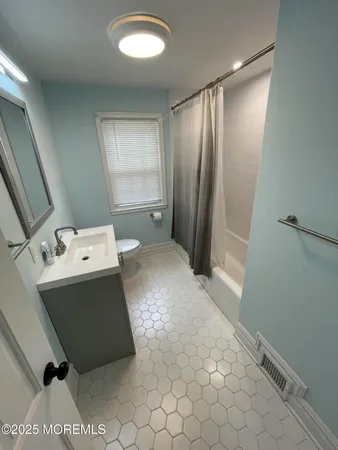 a living room with a baby crib furniture a sink and a refrigerator