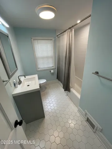 a living room with a baby crib furniture a sink and a refrigerator