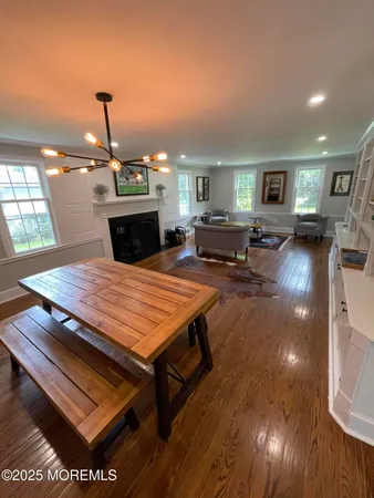a living room with furniture a fireplace and a dining table with wooden floor