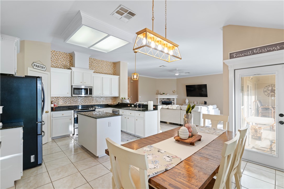 2601 Wool Drive Corpus Christi, TX 78414 - Photo 7 of 25 a kitchen with stainless steel appliances kitchen island granite countertop a refrigerator a stove a sink a dining table and chairs with wooden floor