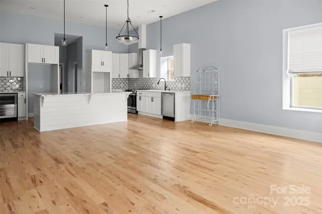 a large kitchen with kitchen island a stove a sink a refrigerator and white cabinets with wooden floor