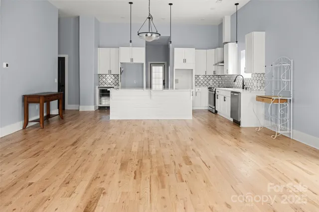 a large kitchen with stainless steel appliances kitchen island granite countertop a refrigerator a stove a sink dishwasher and white cabinets with wooden floor