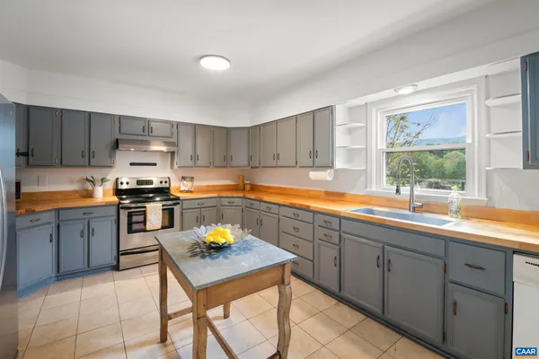 a kitchen with a sink a stove a refrigerator cabinets and a window