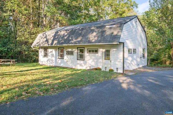 a view of a house with a yard plants and large tree