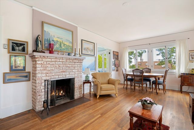 a living room with furniture a fireplace wooden floor and a large window
