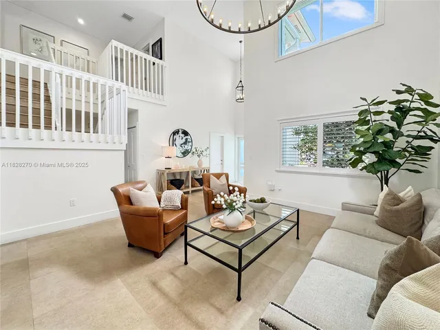 a living room with furniture a chandelier and a potted plant