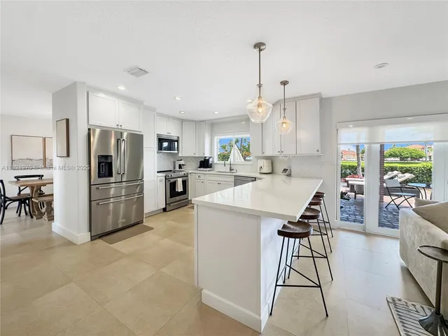 a kitchen with stainless steel appliances kitchen island granite countertop a sink and a refrigerator