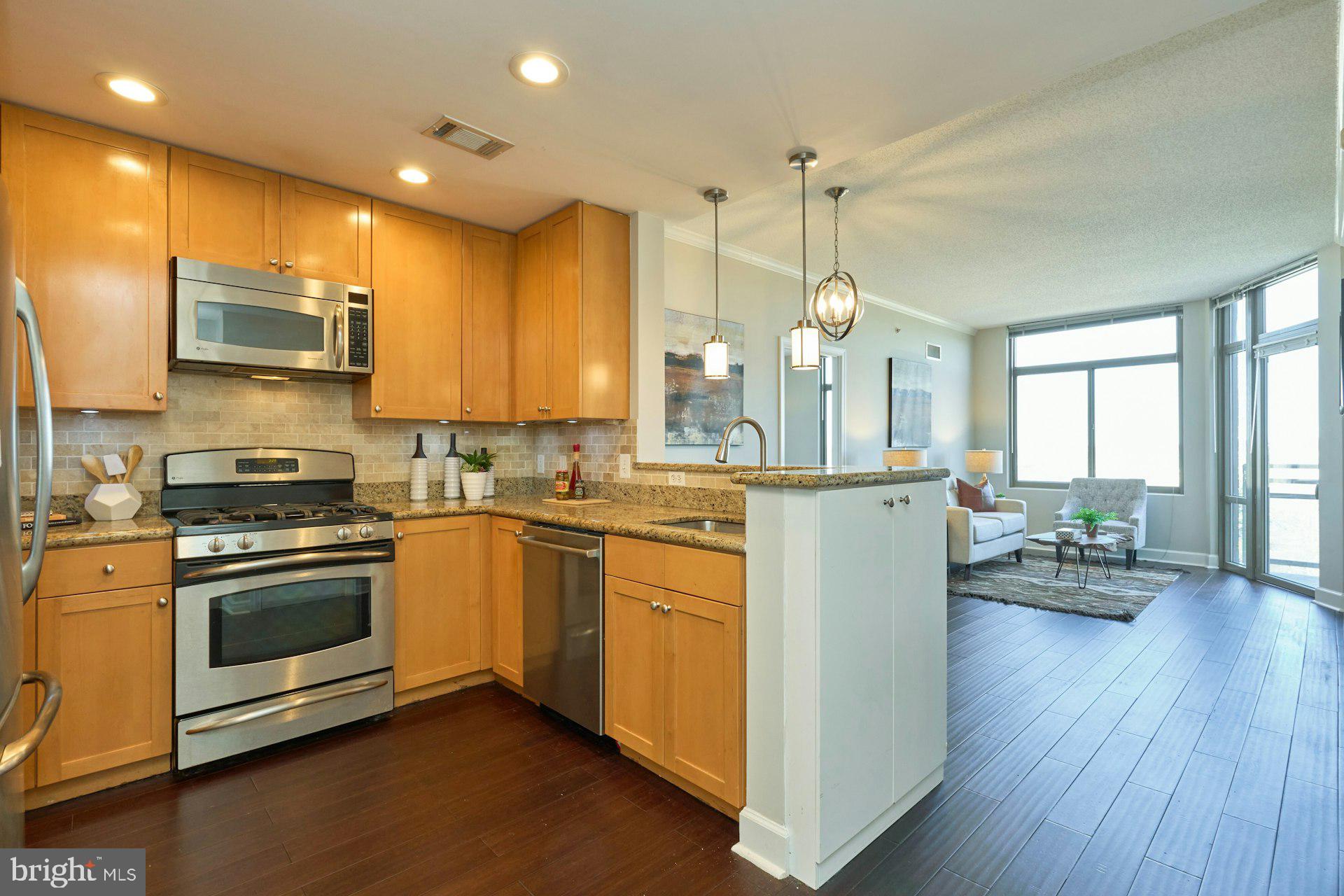 3650 South Glebe Road, Unit 652 Arlington, VA 22202 - Photo 9 of 54 a kitchen with stainless steel appliances granite countertop a refrigerator a stove top oven a sink dishwasher and white cabinets with wooden floor