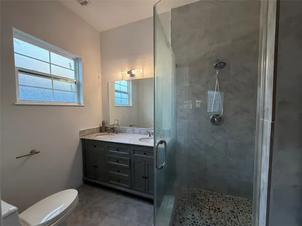 a bathroom with a granite countertop sink a toilet and shower