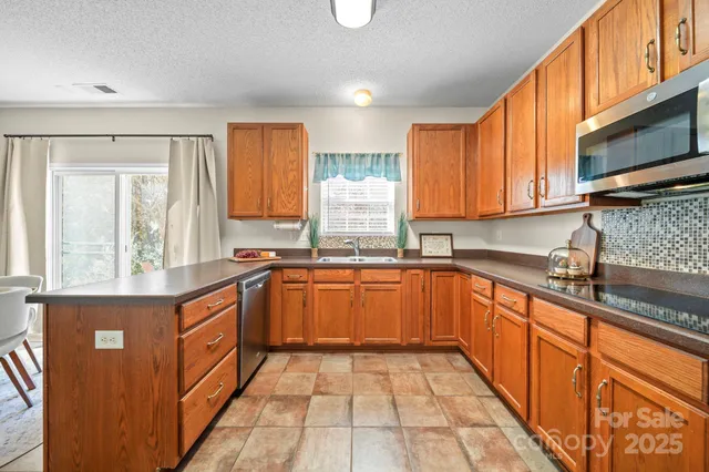 a kitchen with stainless steel appliances granite countertop a stove a sink and a microwave