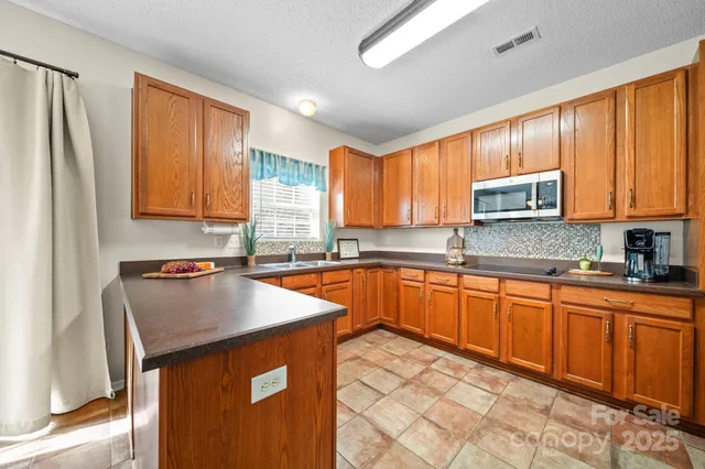 a kitchen with stainless steel appliances granite countertop a sink stove refrigerator and microwave