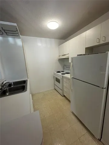 a white refrigerator freezer and a stove sitting inside of a kitchen
