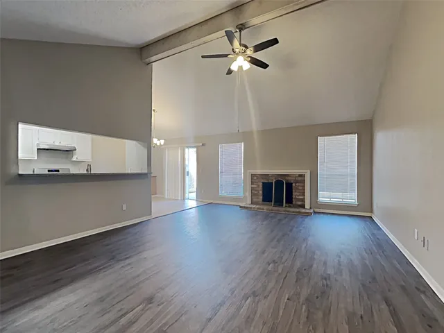 a view of an empty room with wooden floor and a fireplace