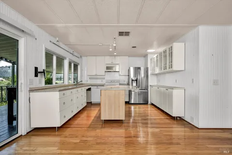 a kitchen with stainless steel appliances granite countertop a white cabinets a sink a stove a refrigerator and white cabinets