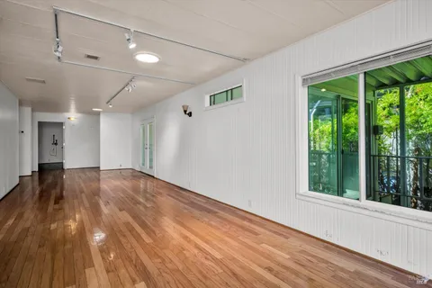 a view of empty room with wooden floor and fan