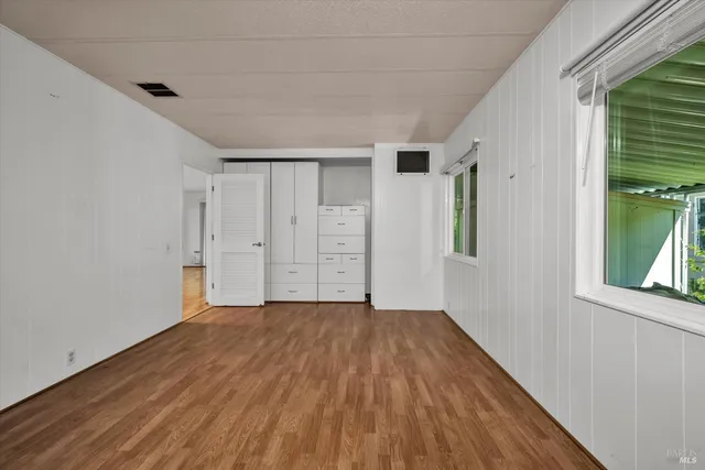 a view of an empty room with window and wooden floor