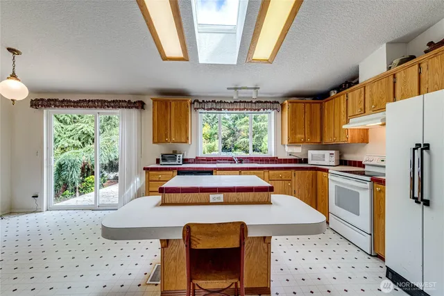 a kitchen with stainless steel appliances kitchen island granite countertop a refrigerator a sink a stove a dining table and chairs with wooden floor