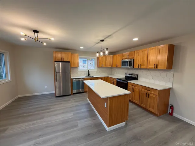 a large kitchen with stainless steel appliances granite countertop a stove a refrigerator a sink dishwasher and a oven with wooden floor