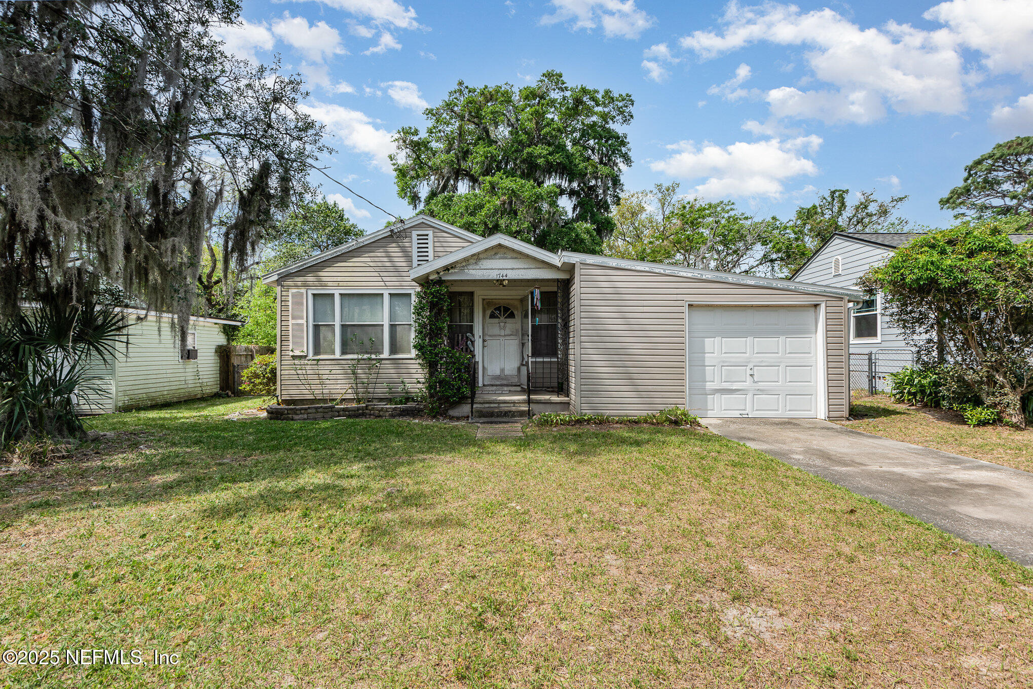 a view of a house with a yard and large tree