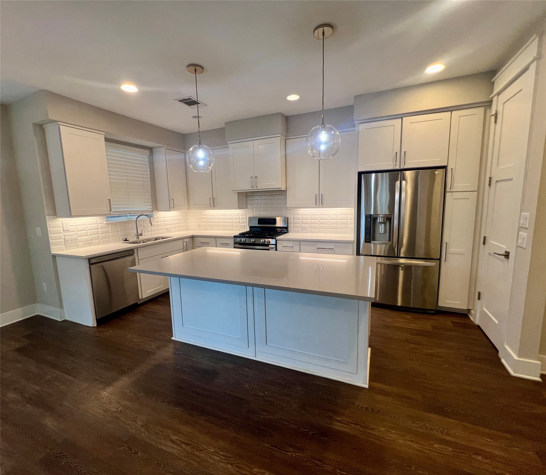 6515 Davis Lane, Unit 10 Austin, TX 78749 - Photo 4 of 22 A contemporary kitchen features an island, ample cabinetry, and rich hardwood flooring, all illuminated by recessed and pendant lighting.