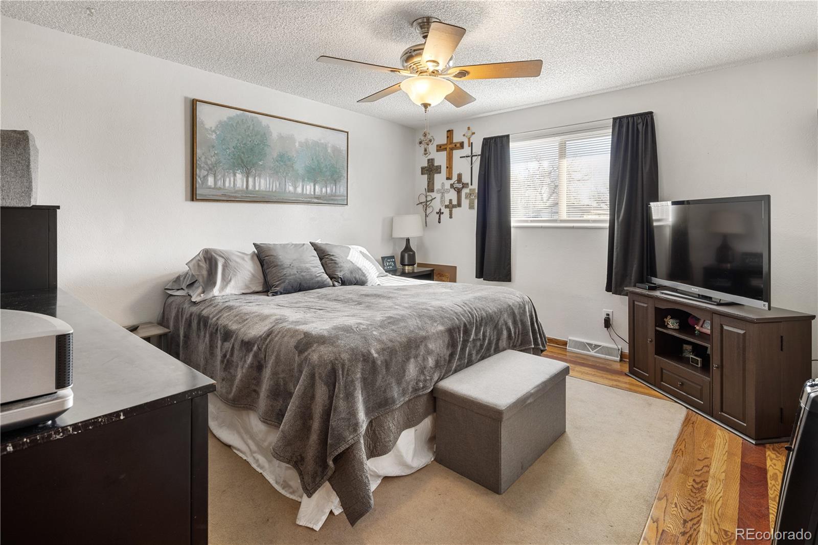 4615 Quail Street Wheat Ridge, CO 80033 - Photo 10 of 29 a spacious bedroom with a bed and a flat screen television